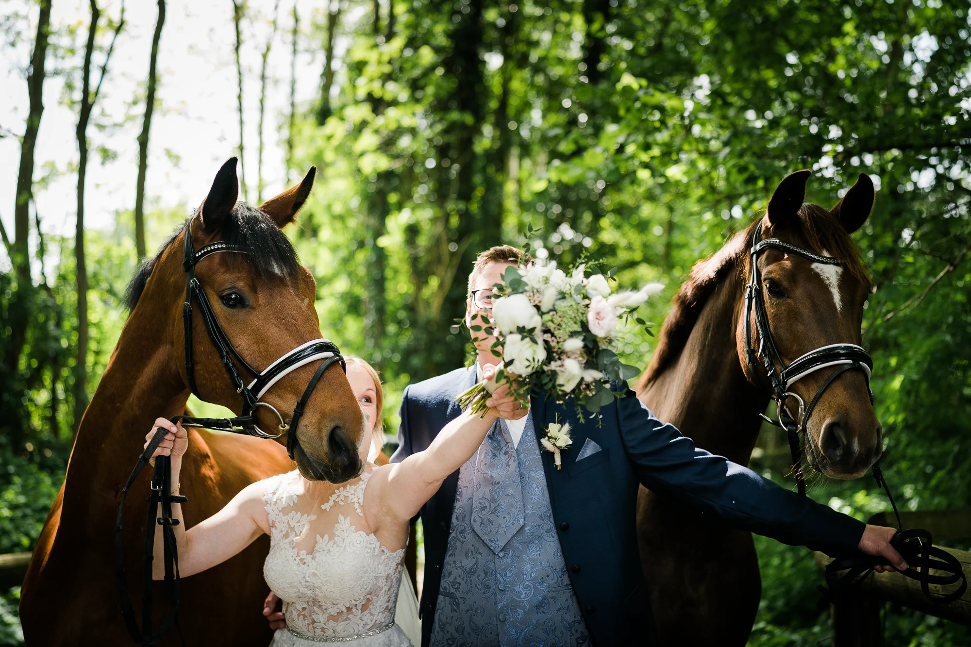 Brautpaar steht mit den eigenen Pferden der Braut im Wald – ein persönlicher Moment am Hochzeitstag