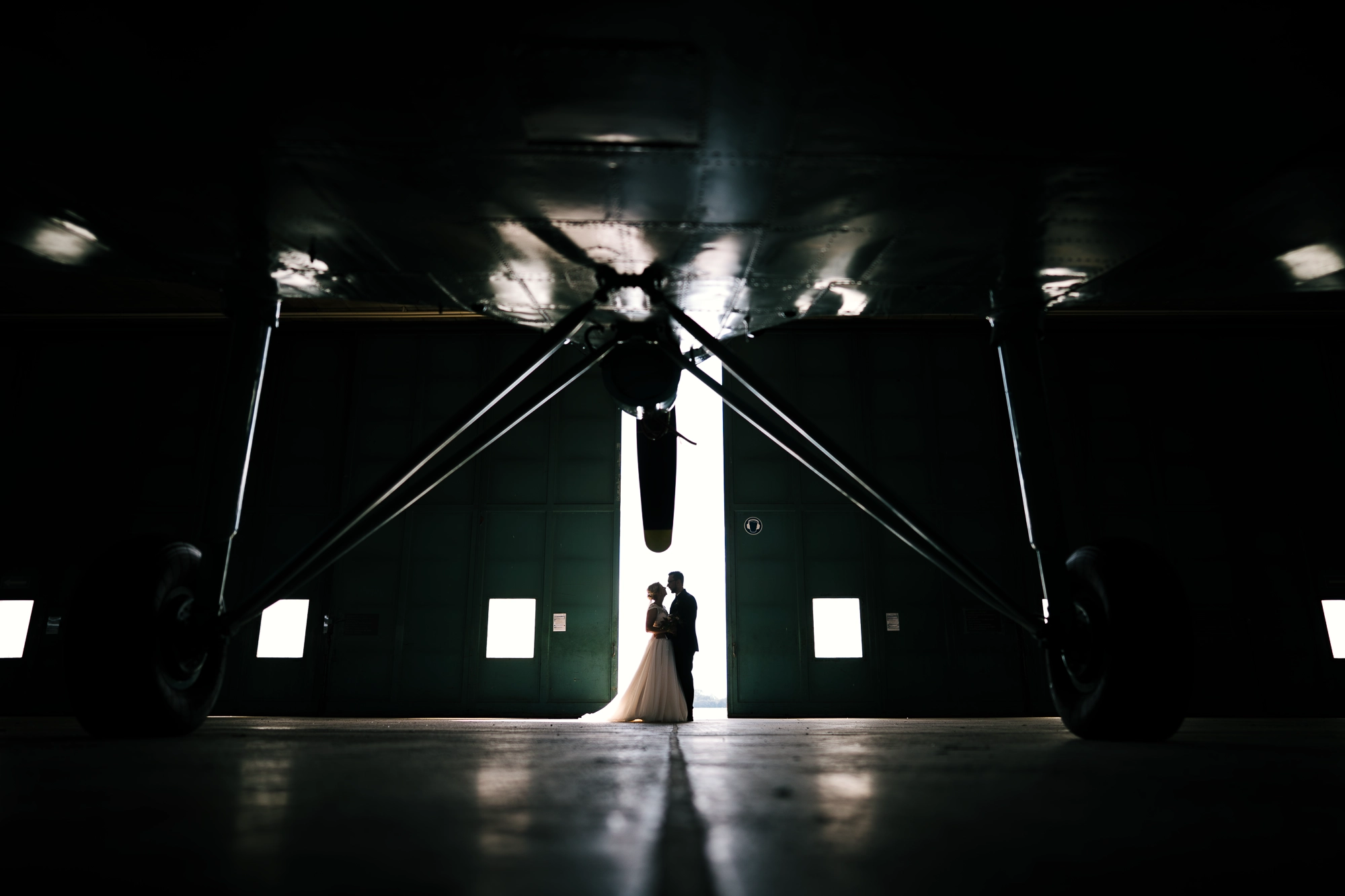 Brautpaar als Silhouette unter einem Flugzeug im Hangar des Flugplatzes Rheine-Bentlage