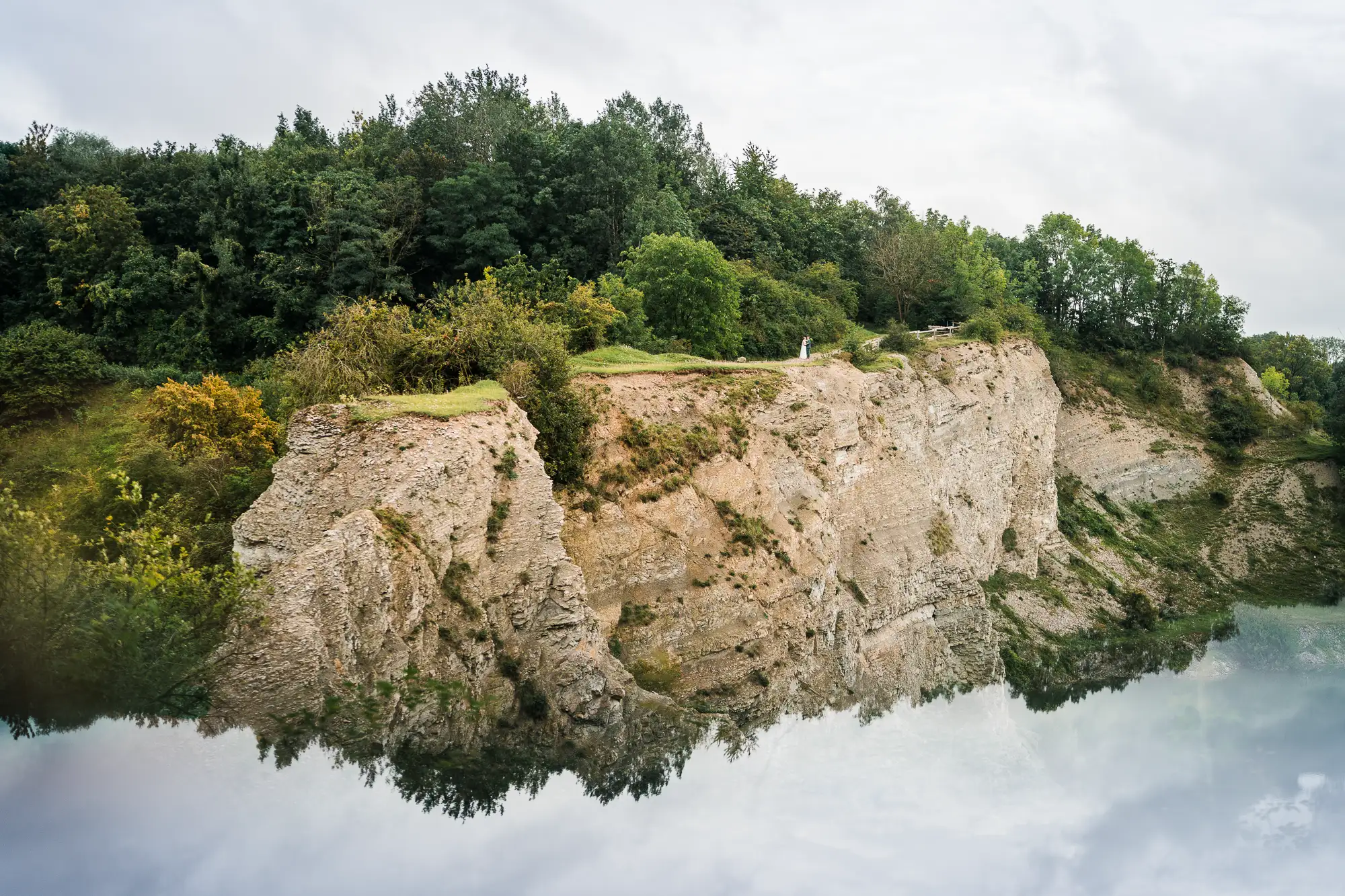 Brautpaar steht winzig klein auf den Felsen des Naturschutzgebiets Waldhügel - Hochzeitsfotograf Rheine
