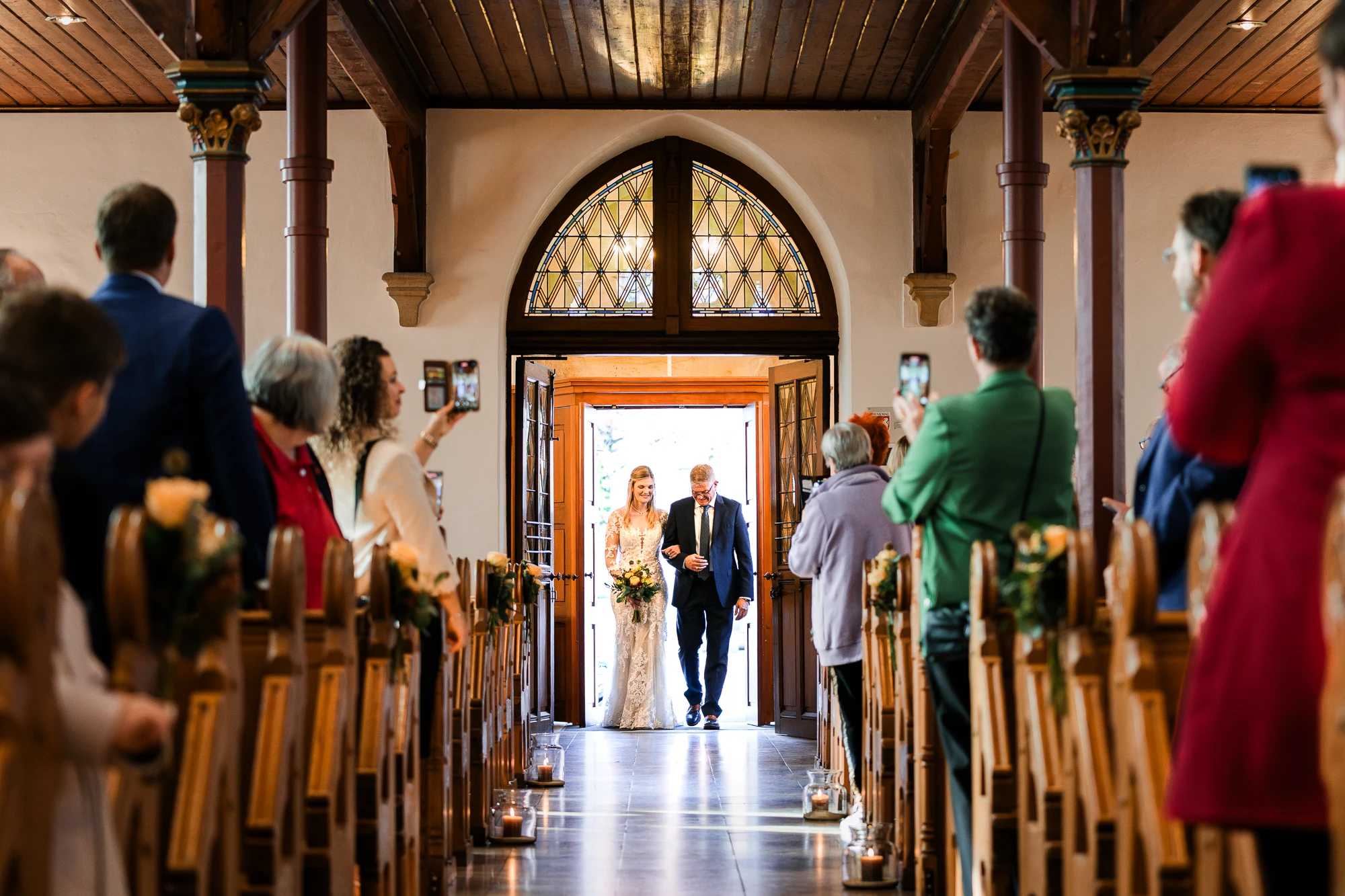 Braut betritt mit ihrem Vater die Kirche zum Einzug bei einer Hochzeit in Rheine und wird zum Traualtar geführt, während die Hochzeitsgäste gespannt zuschauen